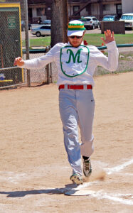 Photo by Larry Ferguson. Manitou’s Will Bishop records an “ace” as he crosses home base in the first inning.