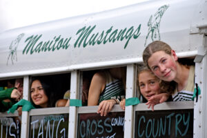Photo by Rhonda Van Pelt. Members of the girls cross-country team peek out of bus windows during the parade. From left: Kara Donegan, Ellen Lowe and Rylynne Murphy Skillen.