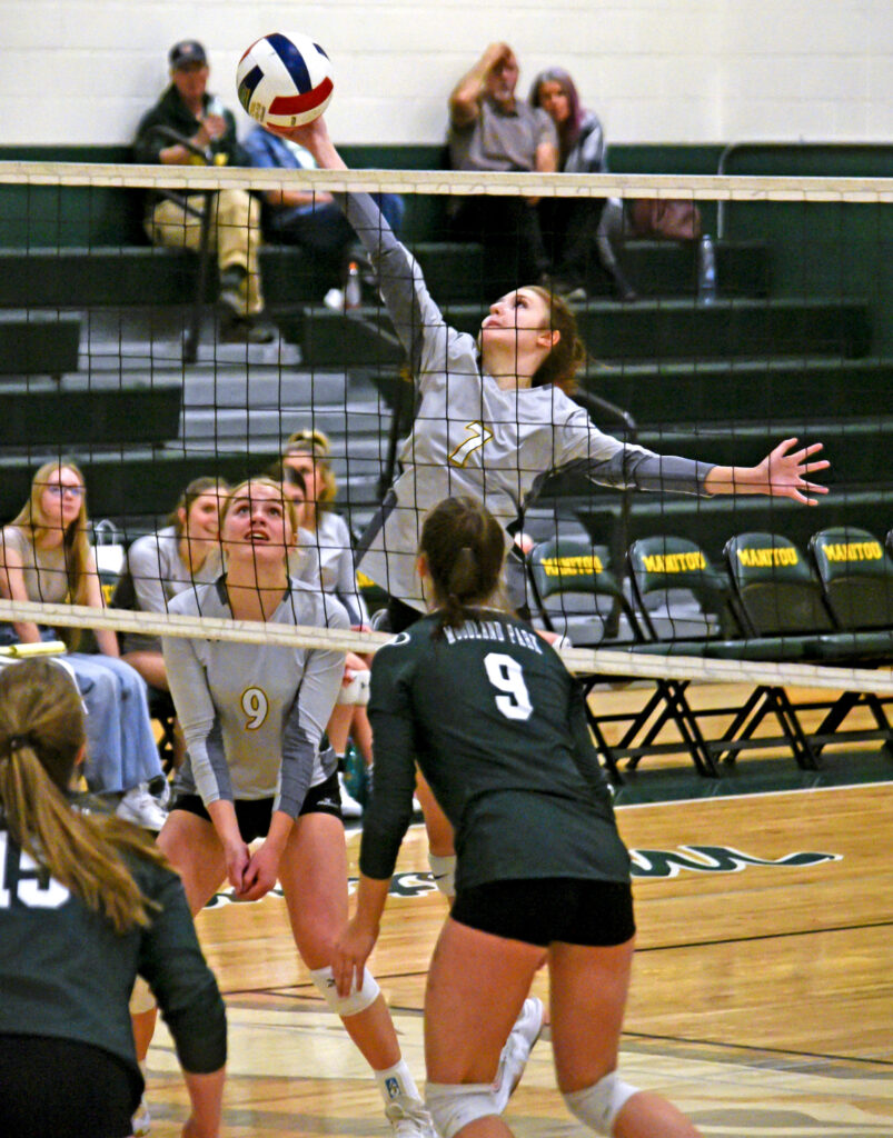 Photo by Bryan Oller. Hannah Ruger defends the net during the Mustangs’ match against Woodland Park. Sierra Dunlap (9) waits to see what will happen.