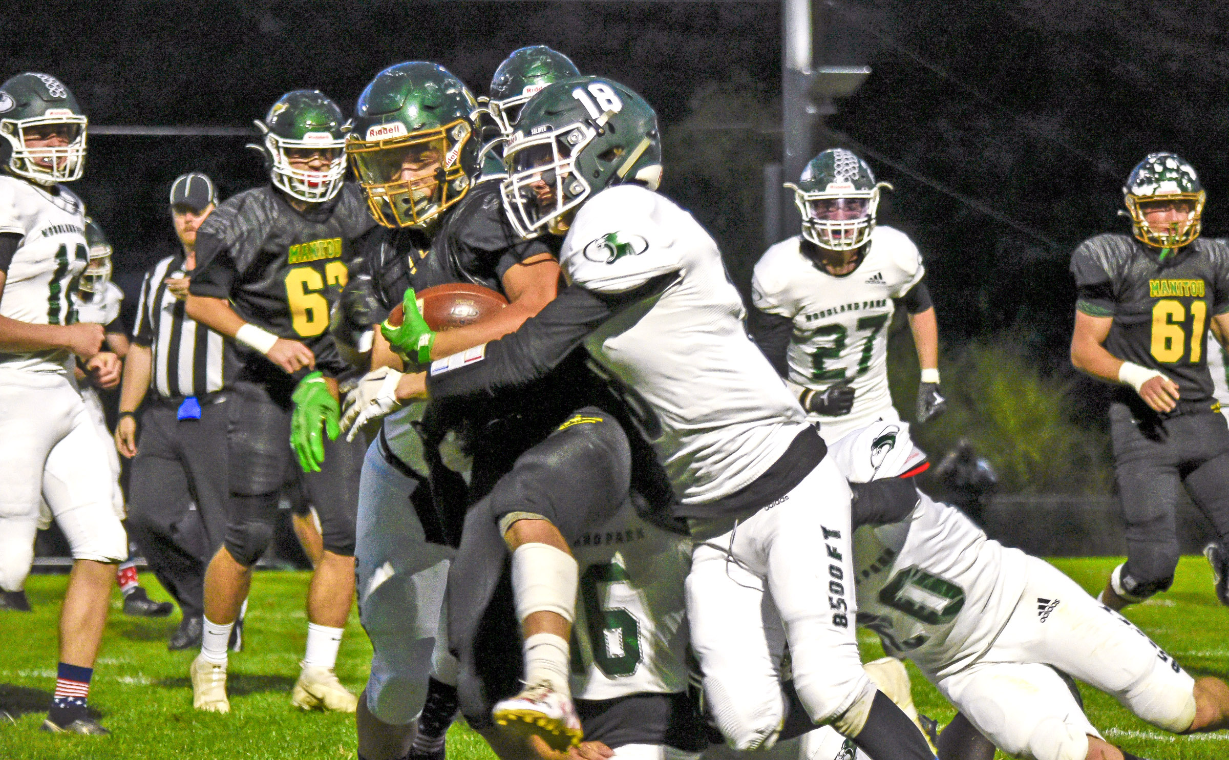 Photo by Bryan Oller/ Mustang Tyler Maloney is surrounded by Woodland Park players as he carries the ball during the Sept. 30 Homecoming game. In the background: Will Cittadino, left, and Bradyn Dowling.