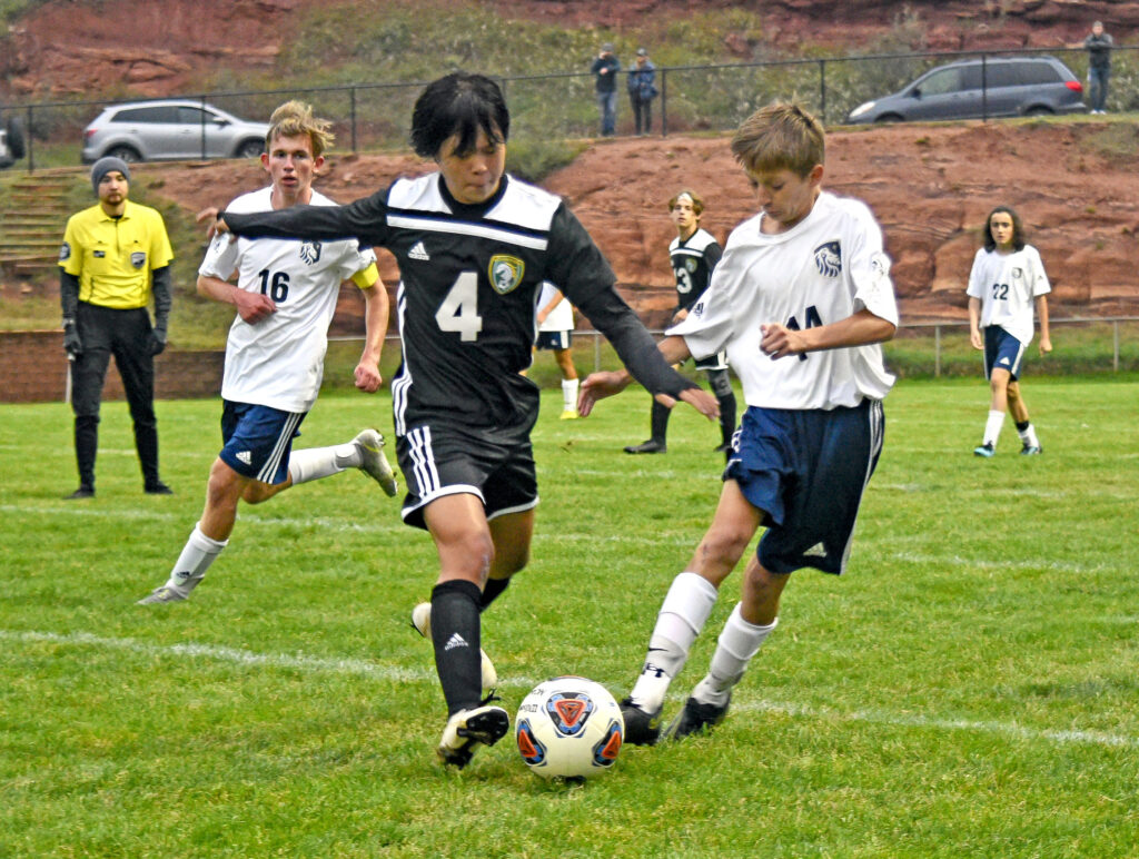 Photo by Bryan Oller. Graham Beckum fends off a Colorado Springs Christian School player during their match.