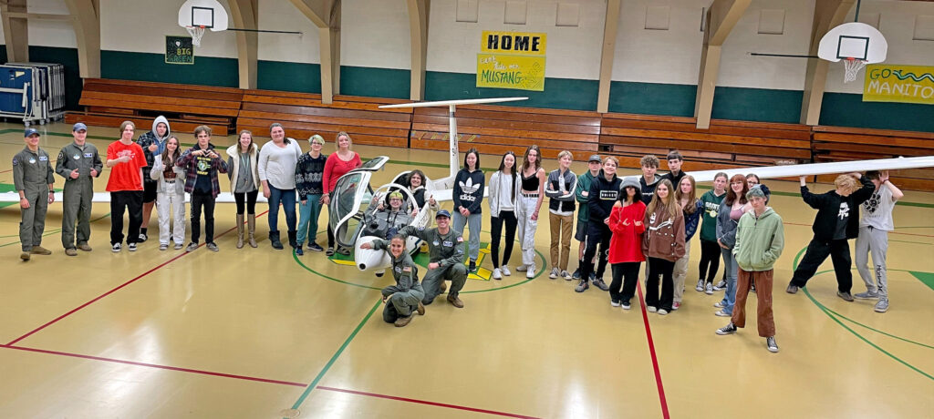 Photo Courtesy of Manitou Springs School District 14. Students, cadets and teachers gather around the glider in the school gym.